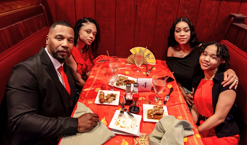 A man in a suit and tie is sitting at a table with two girls.