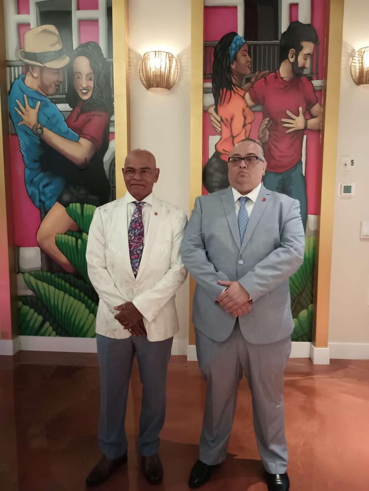 Two men in suits are standing in front of a painting