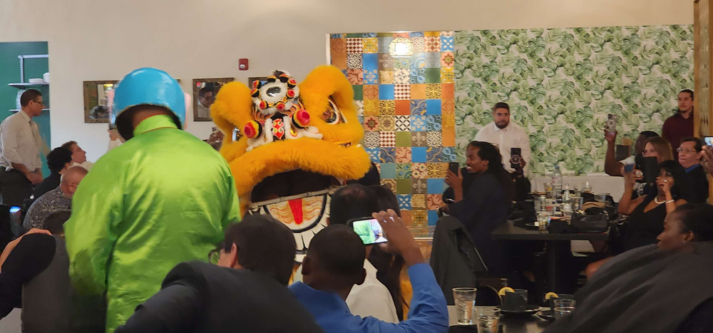 A group of people are watching a lion dance in a room.