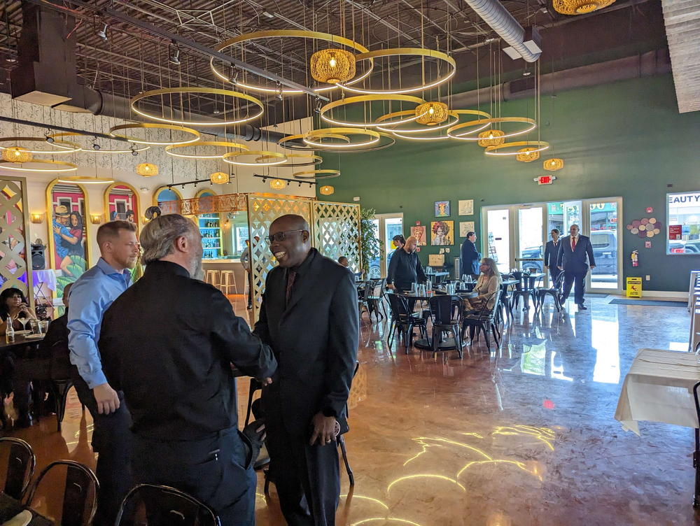 A group of men are standing in a restaurant talking to each other.