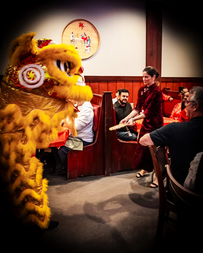 A woman is standing in front of a lion costume in a restaurant.