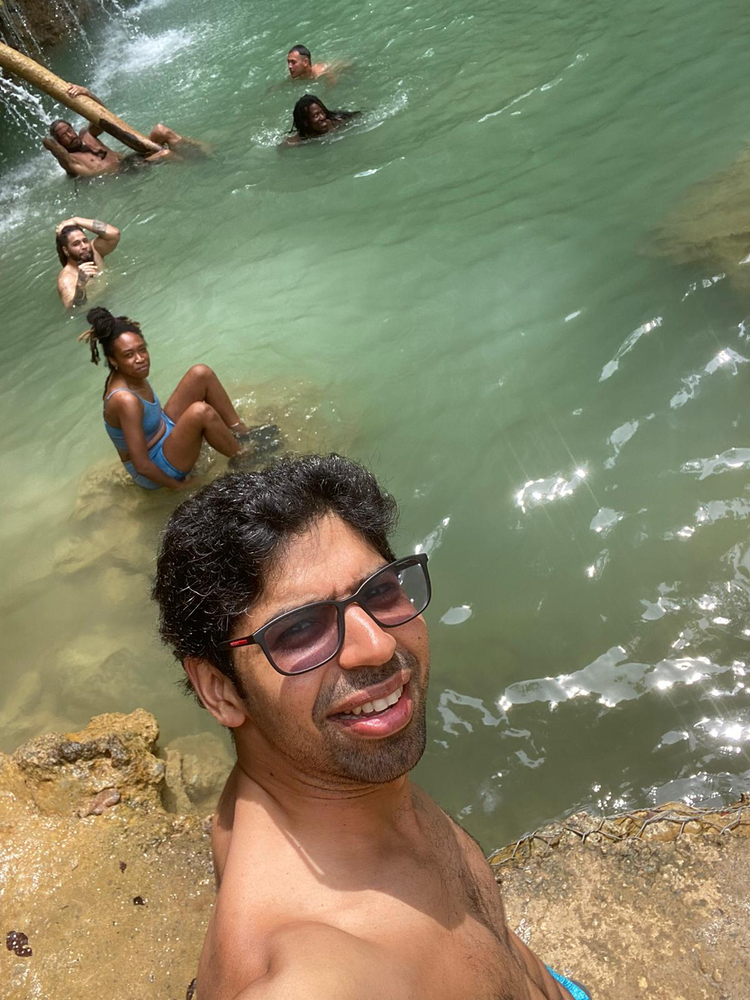 A man is taking a selfie in the water while people are swimming in the water.