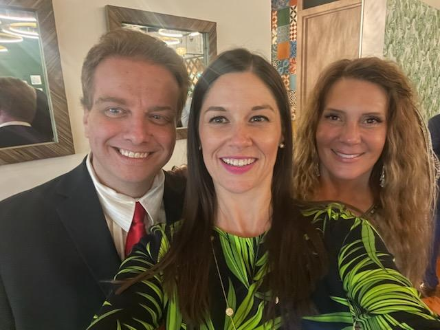 A man in a suit and tie is posing for a picture with two women.