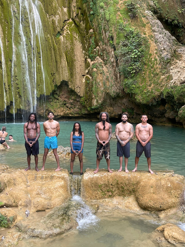 A group of people are standing on rocks in front of a waterfall.