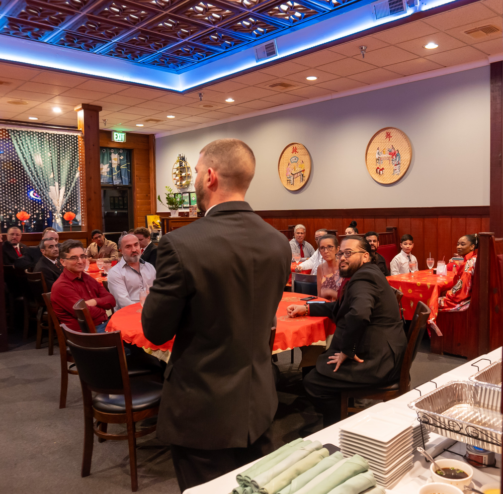 A man in a suit is giving a presentation to a group of people in a restaurant