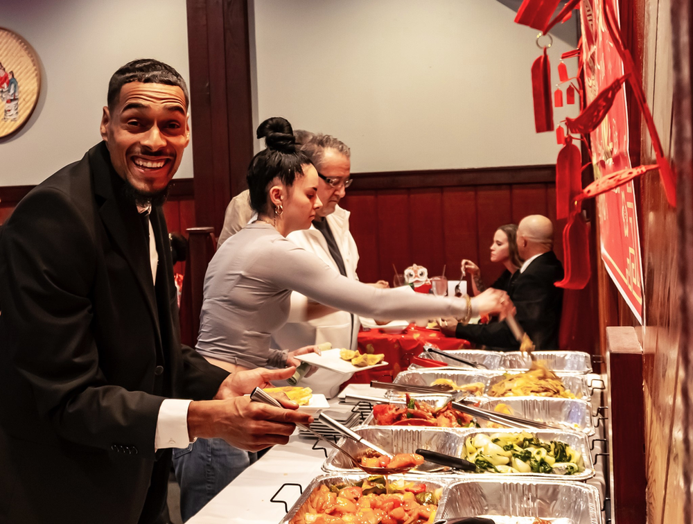 A man in a suit is standing in front of a buffet line.