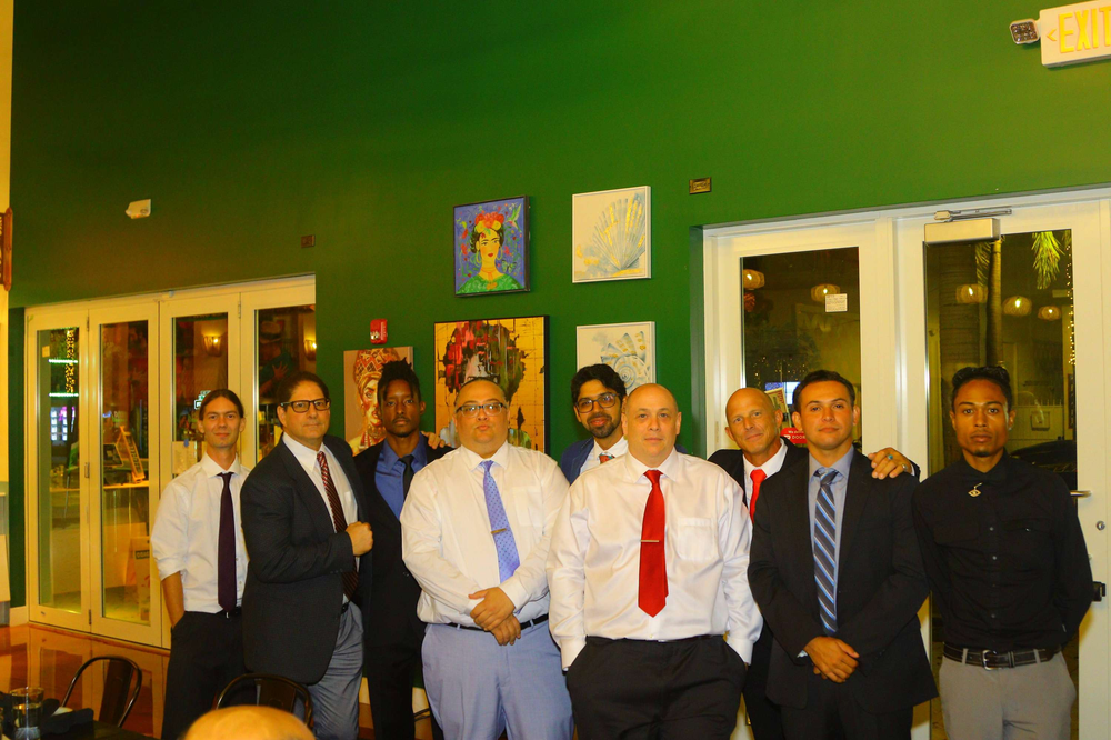 A group of men are posing for a picture in front of a green wall.