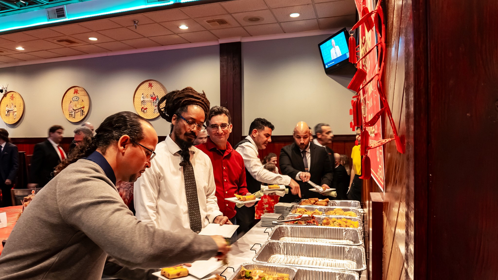 A group of people are standing around a buffet line in a restaurant.