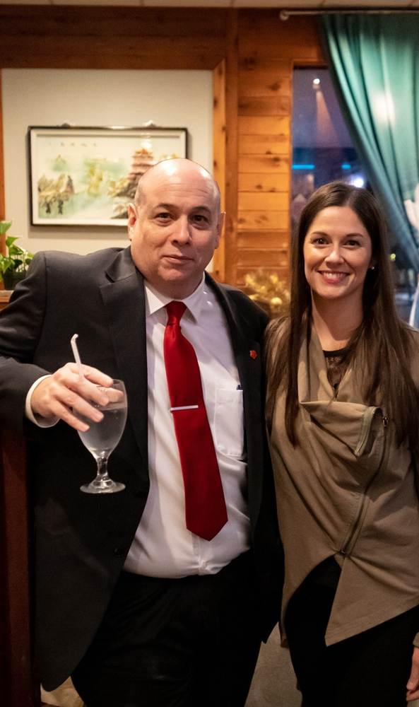 A man in a suit and tie is holding a glass of water next to a woman.