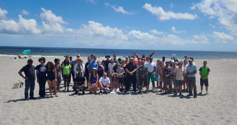 A large group of people are posing for a picture on the beach.