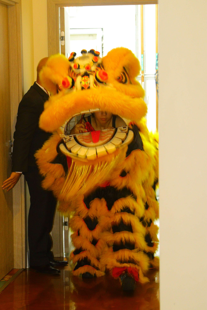 A man is standing next to a lion costume in a hallway.