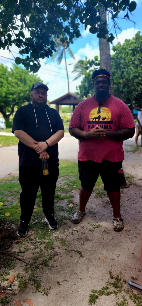 Two men are standing next to each other on the side of the road.