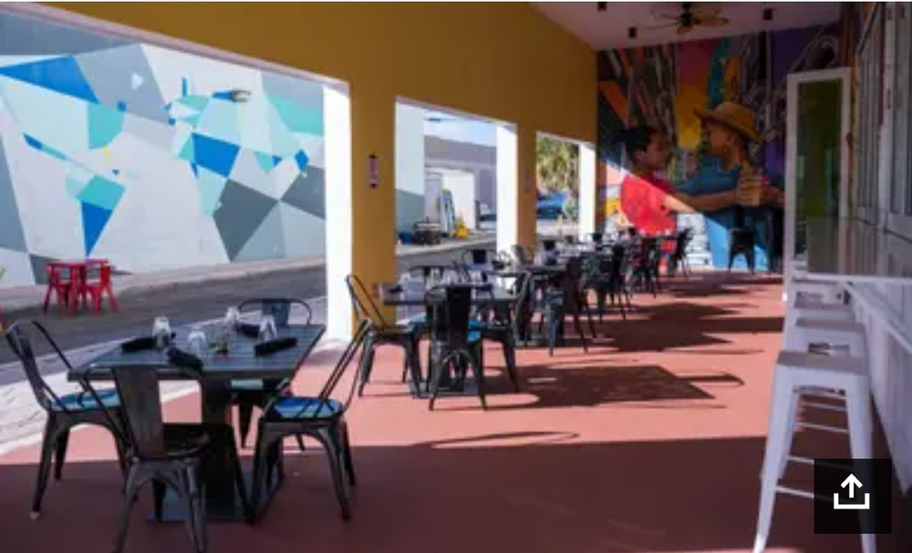 A restaurant with tables and chairs and a mural on the wall.