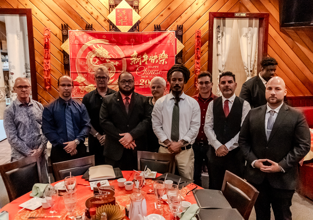 A group of men are standing around a table in a restaurant.