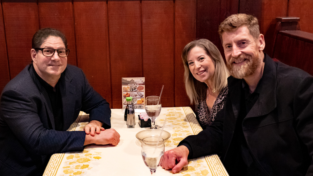 Three people are sitting at a table in a restaurant.