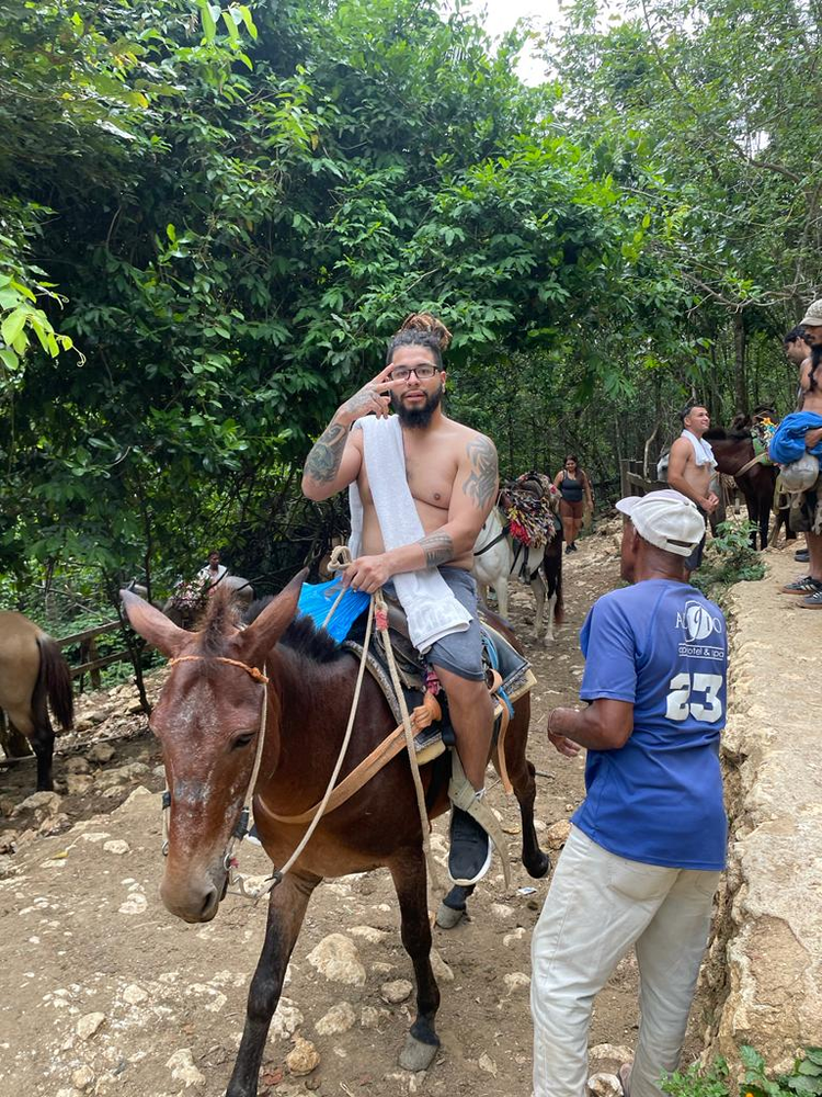 A man is riding on the back of a donkey while talking on a cell phone.