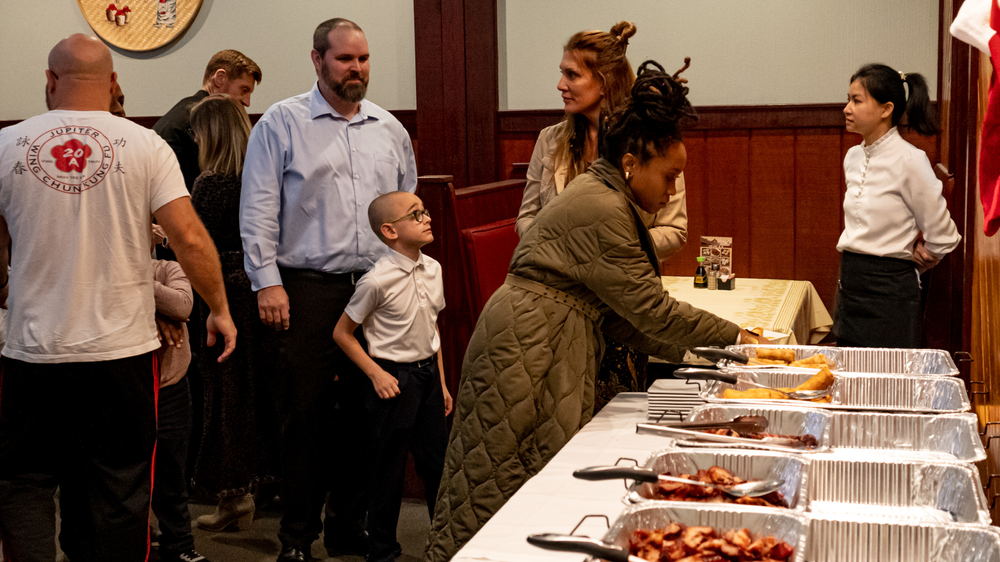 A group of people are standing around a buffet table in a restaurant.