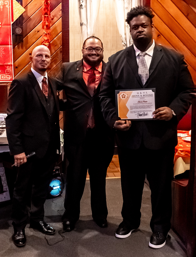 Three men are posing for a picture and one of them is holding a certificate