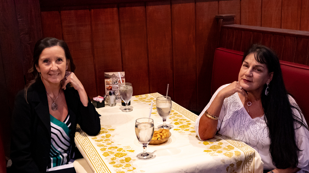 Two women are sitting at a table in a restaurant.