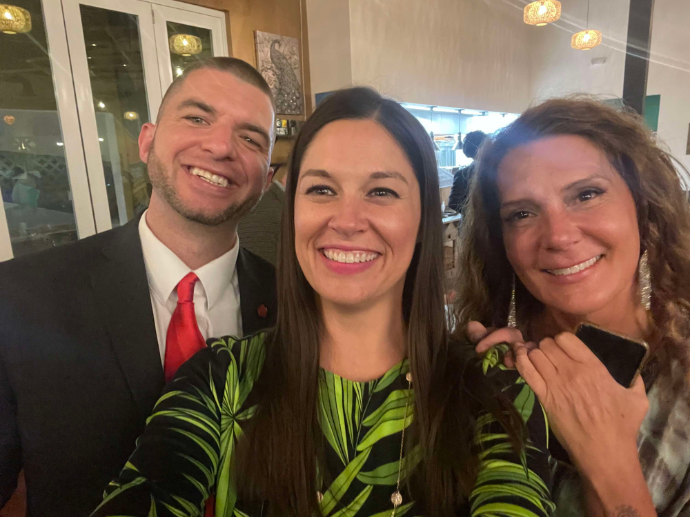 A man in a suit and tie is taking a selfie with two women.