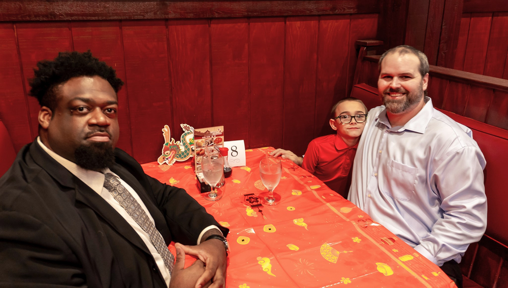 Two men and a boy are sitting at a table in a restaurant.