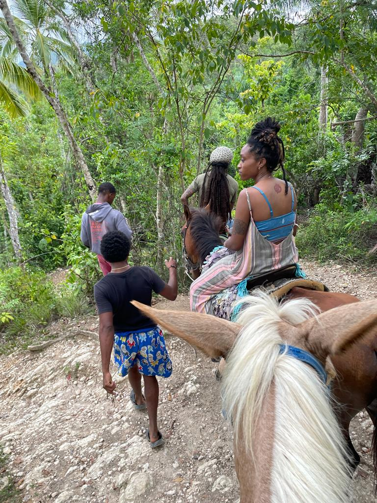 A group of people are riding horses down a dirt path.