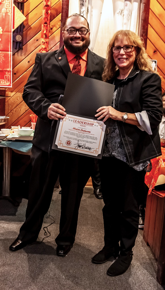 A man and a woman are standing next to each other holding a certificate.