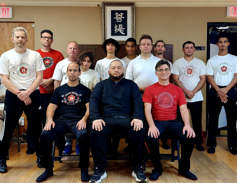 A group of men are posing for a picture in a room with chinese writing on the wall.