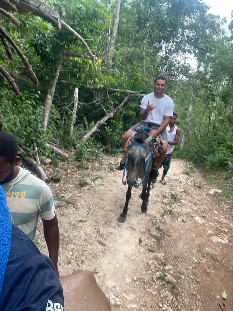 A man is riding a donkey down a dirt road