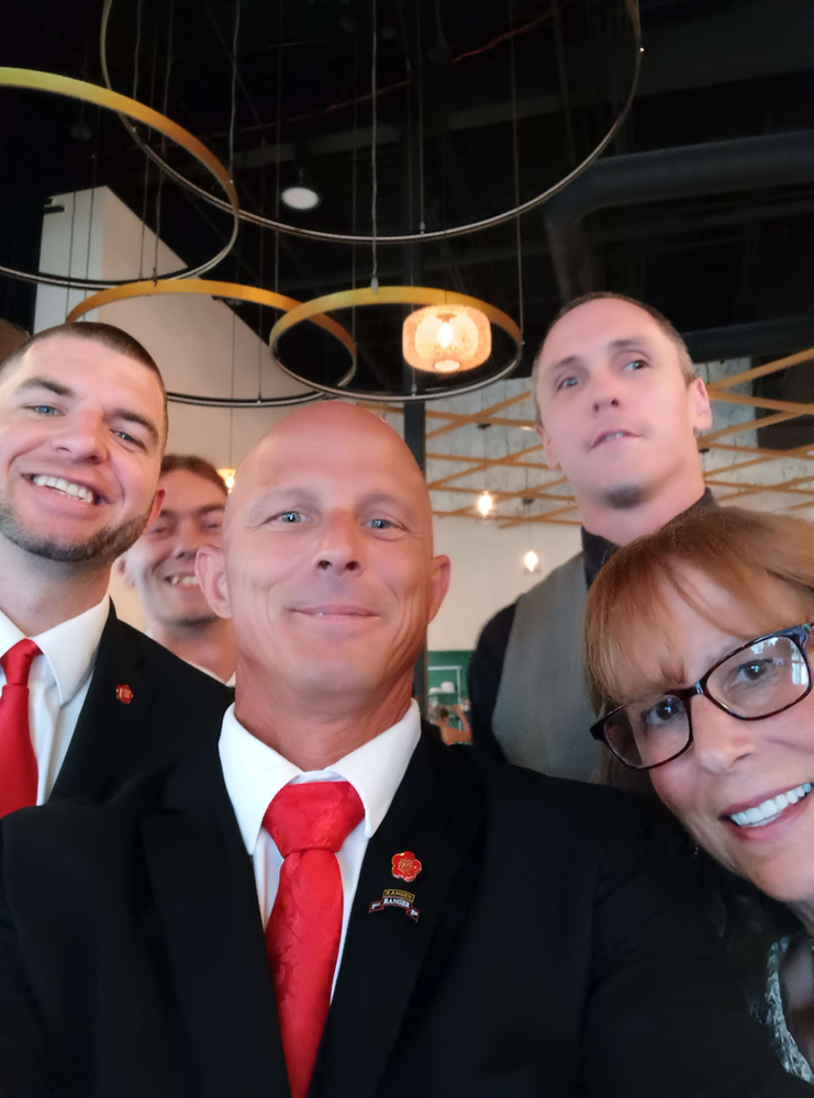 A group of people posing for a picture with one man wearing a red tie