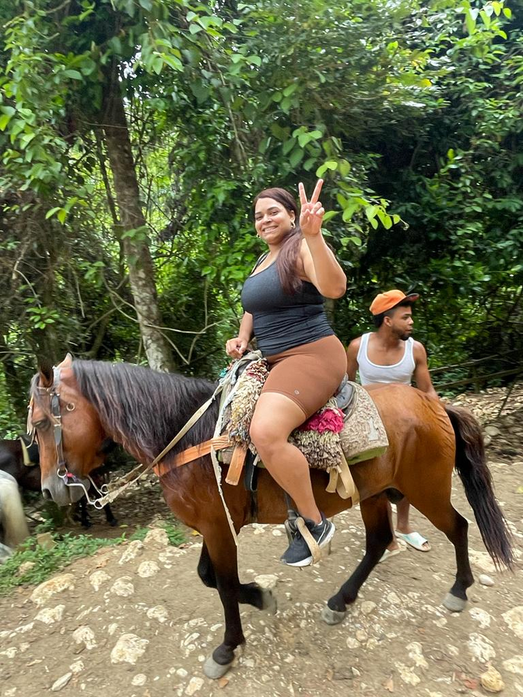 A woman is riding on the back of a brown horse.