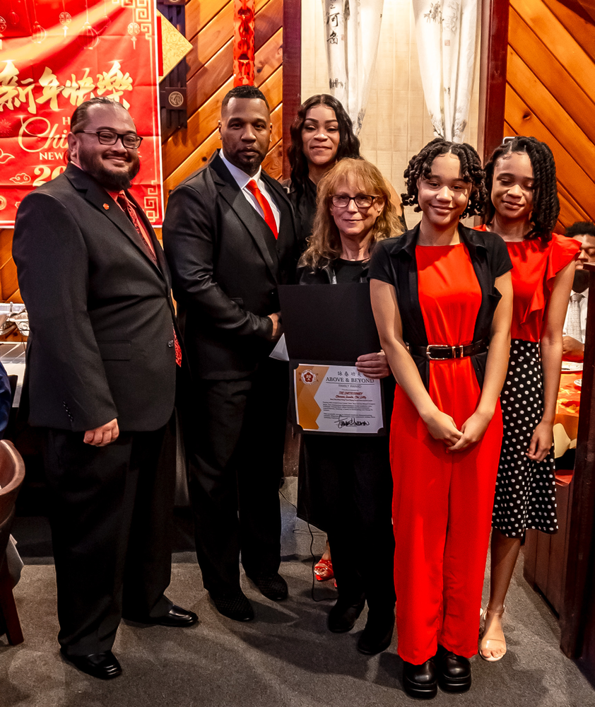 A group of people posing for a picture with one woman holding a certificate