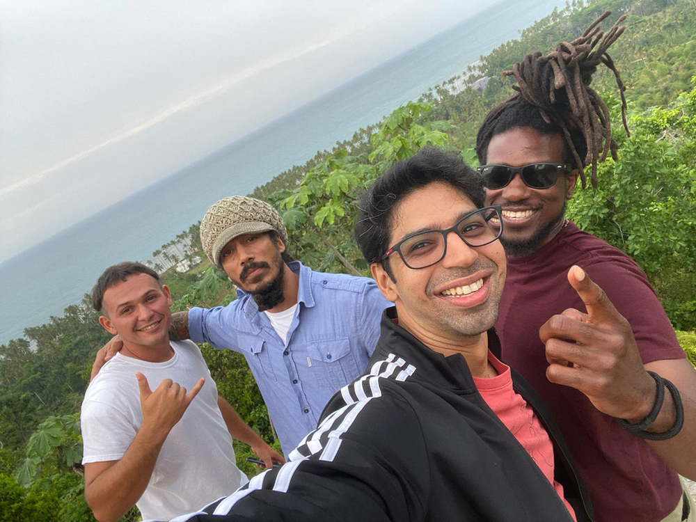 A group of men are posing for a selfie with the ocean in the background.