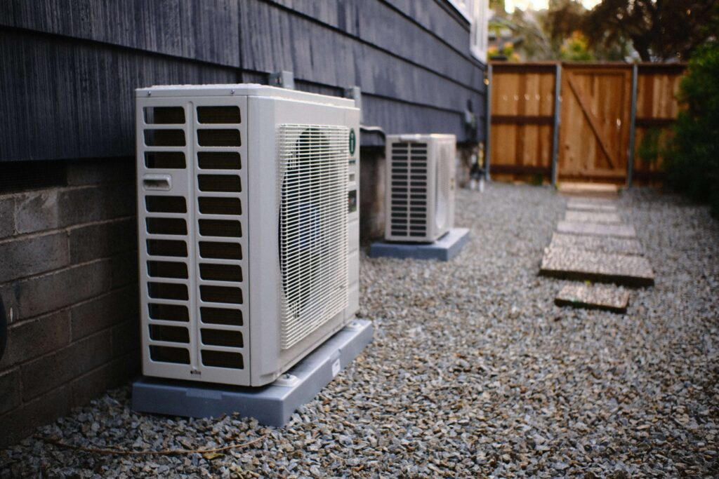 Two air conditioning units outside a building on a gravel patio.