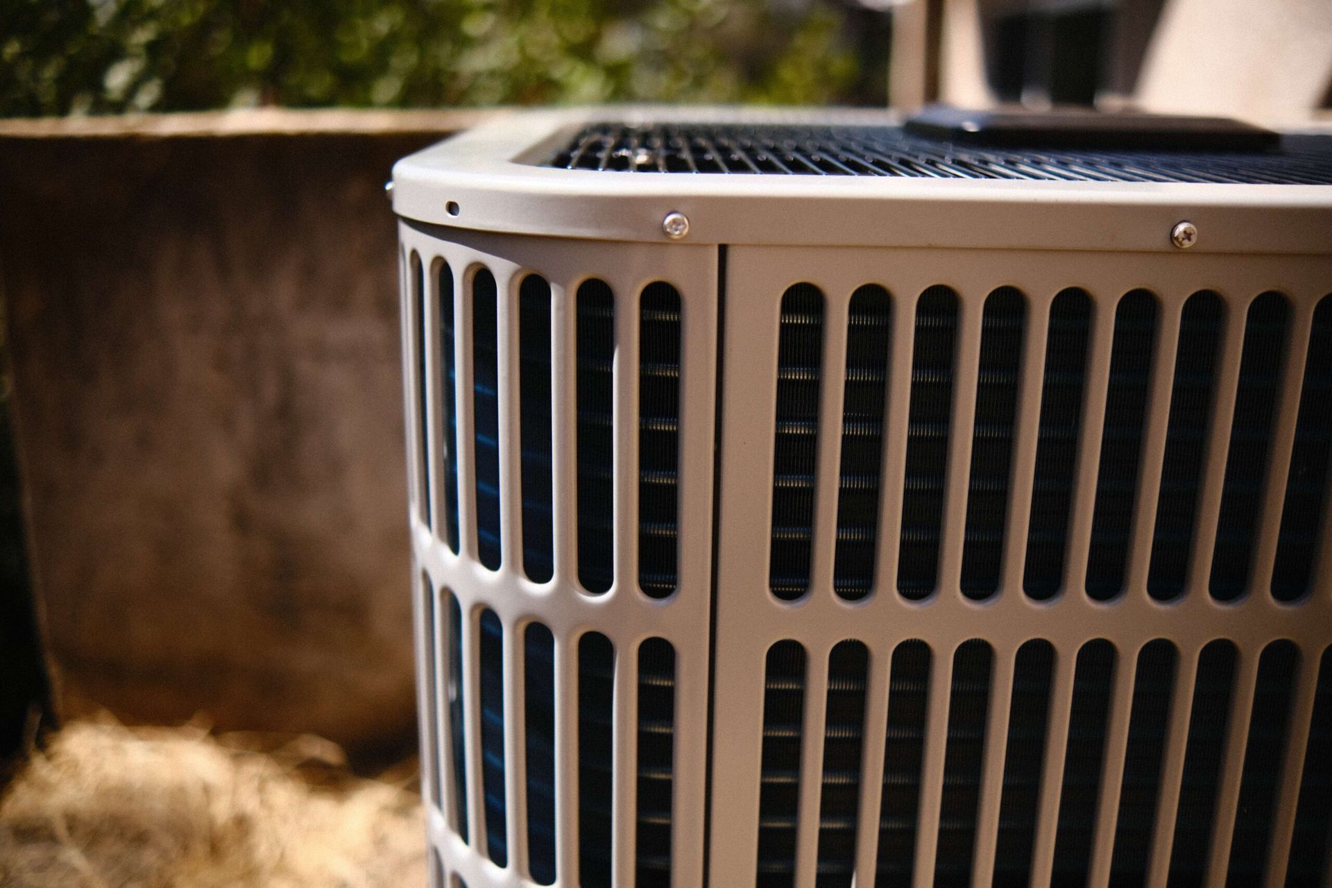 Air conditioning unit with metal grill; outdoors in daylight.