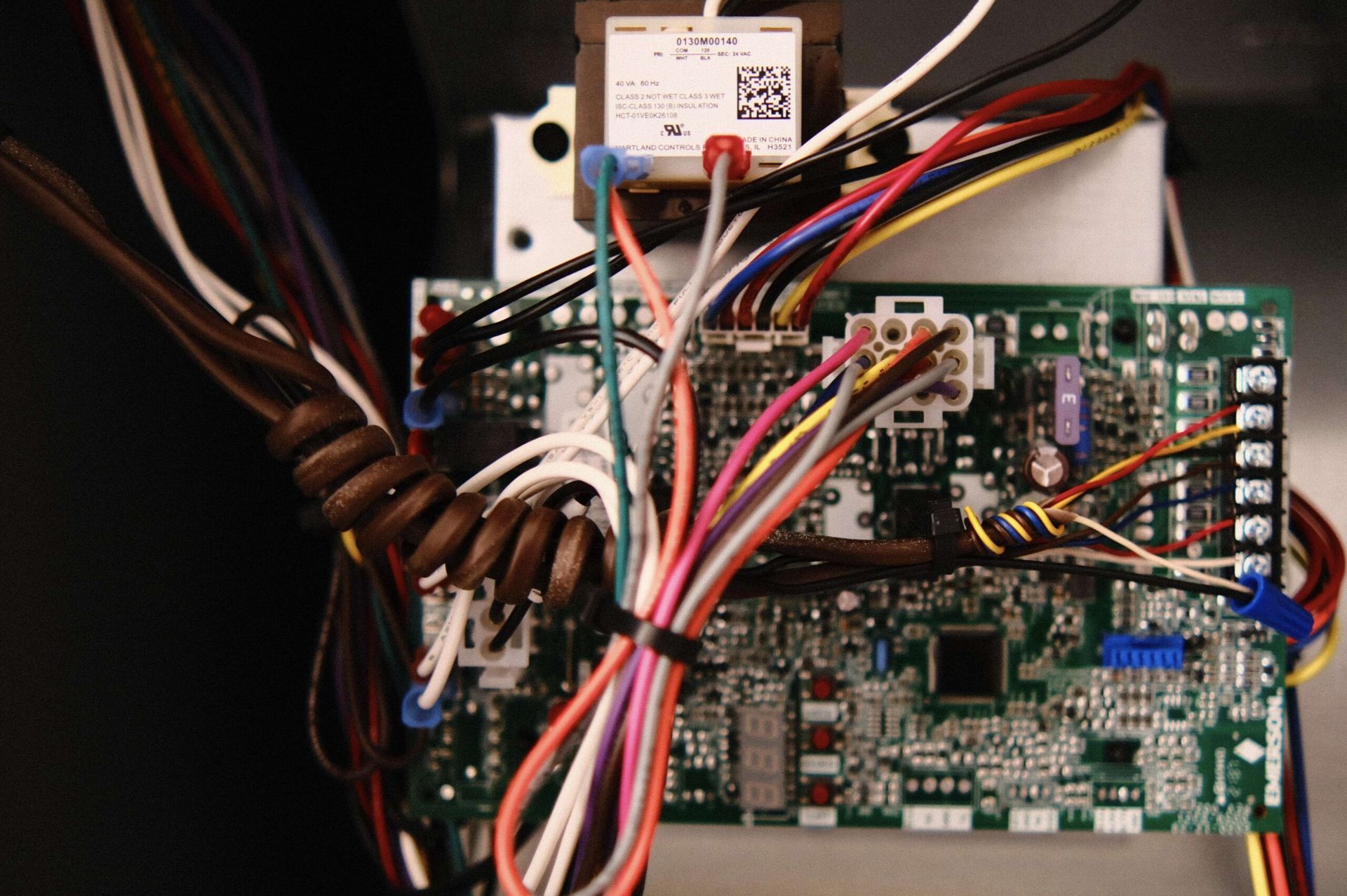 Circuit board with various colored wires and a transformer.