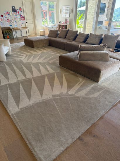 Modern living room with brown sectional sofa and geometric area rug near large windows
