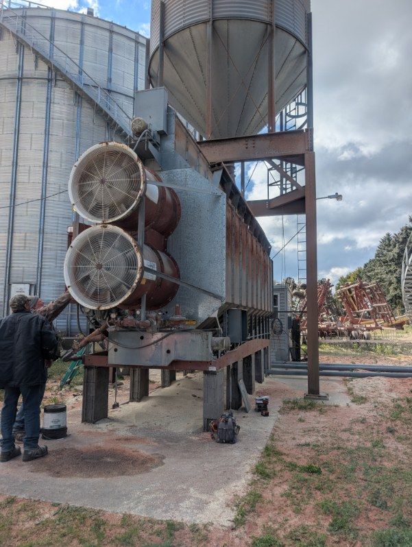 Industrial machinery with large cylindrical tanks and a person standing beside it outdoors under cloudy skies