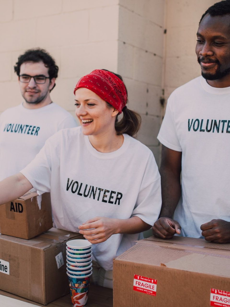 a group of people wearing volunteer shirts are standing around boxes .