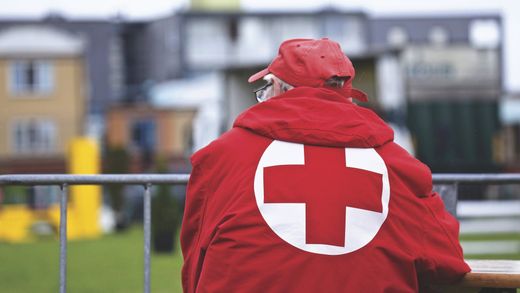 a man wearing a red jacket with a white cross on the back