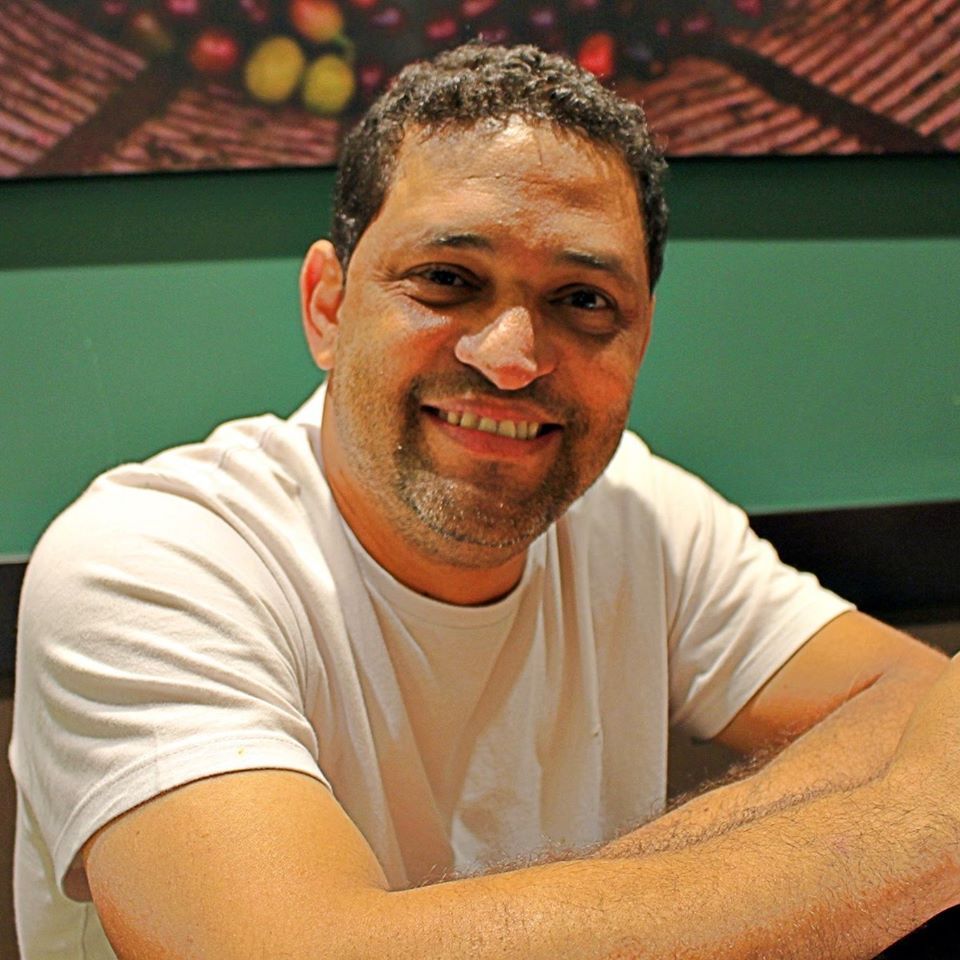 A man in a white shirt is smiling for the camera
