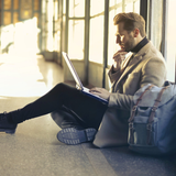 A man is sitting on the floor using a laptop computer