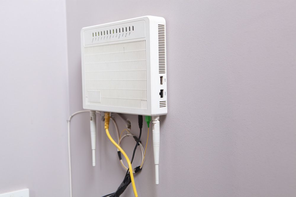 A White Router is Hanging on a Wall With Wires Coming Out of It — Audiomation in Mid North Coast, NSW