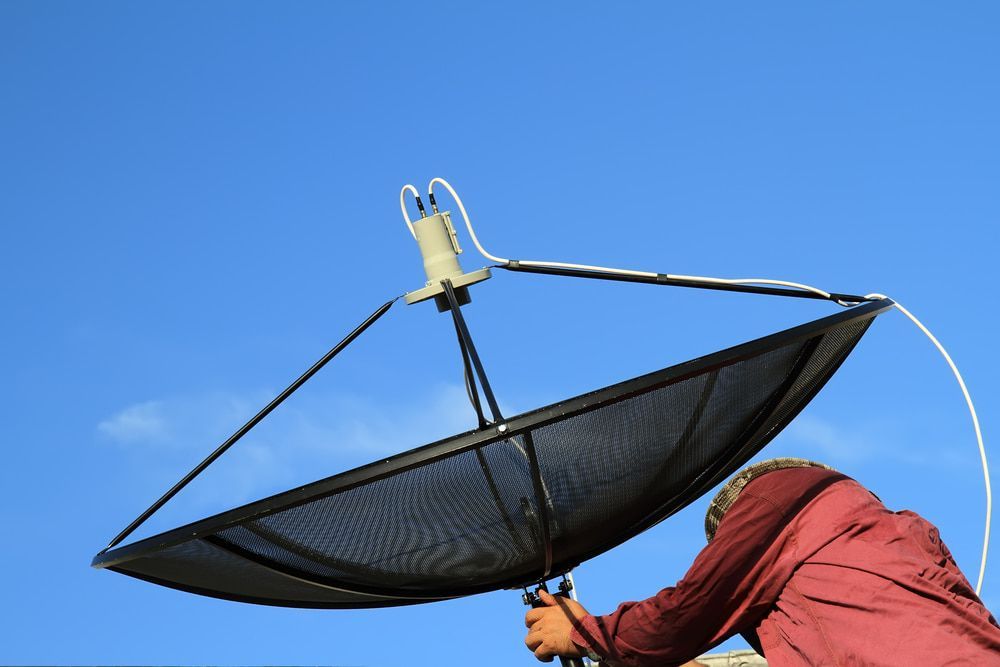 A Man in a Red Jacket is Working on a Satellite Dish — Audiomation in Nabiac, NSW