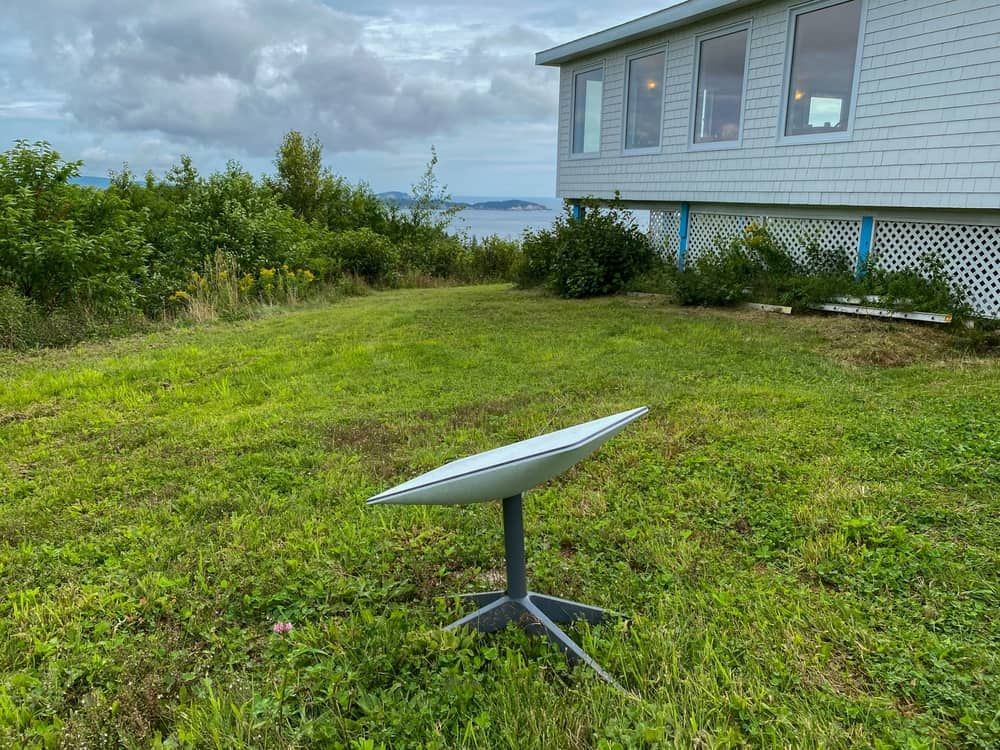 A Satellite Dish is Sitting in the Grass in Front of a House — Audiomation in Taree, NSW