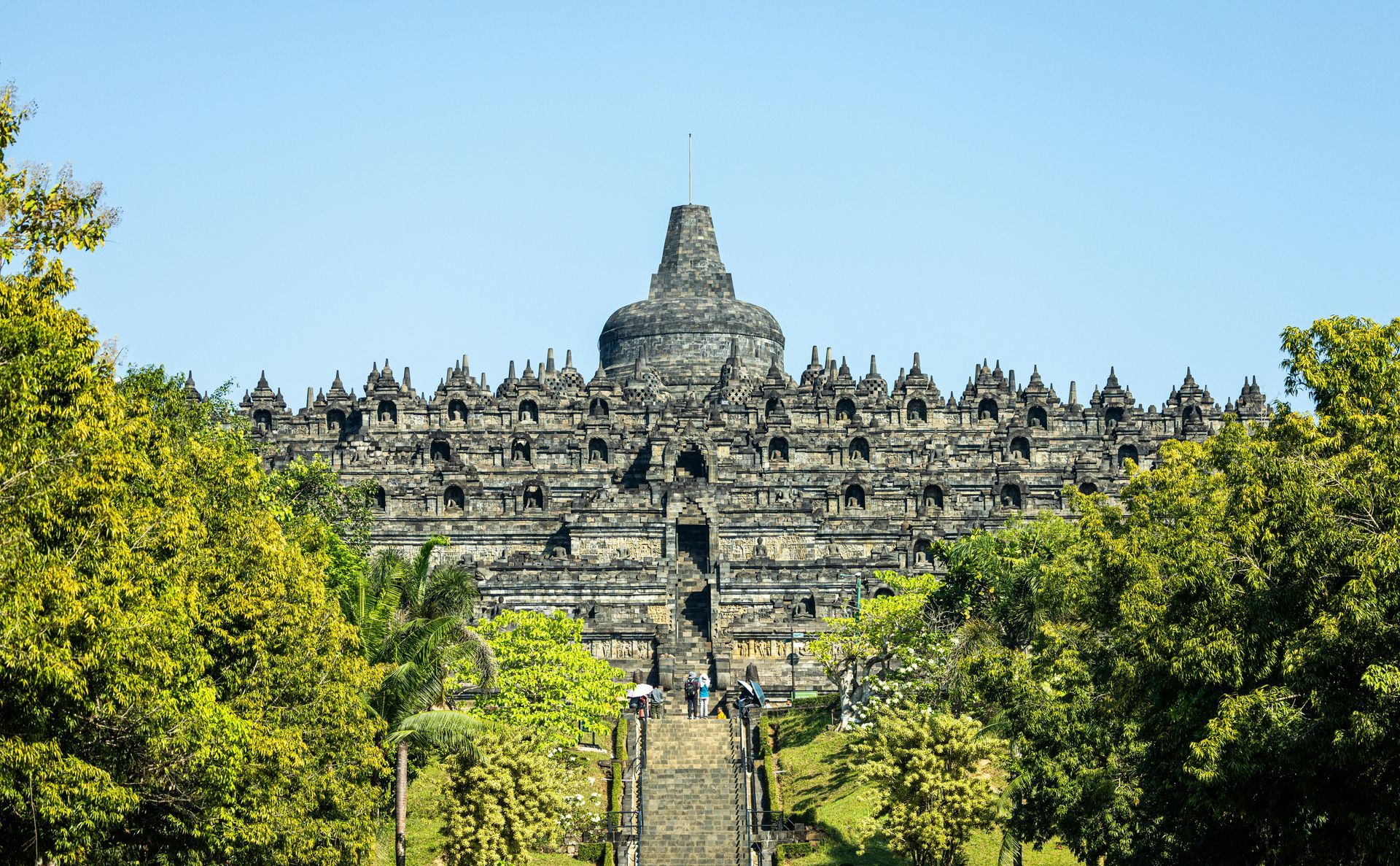 Visitors admiring Borobudur Temple amidst lush green surroundings