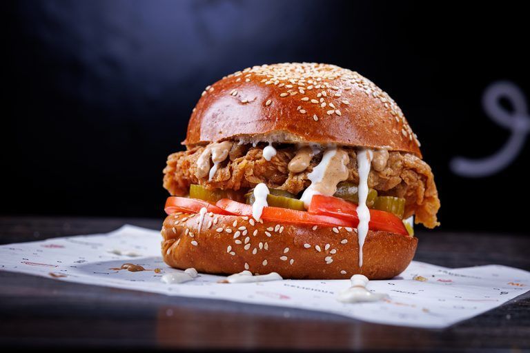 A close up of a chicken sandwich on a bun on a table.