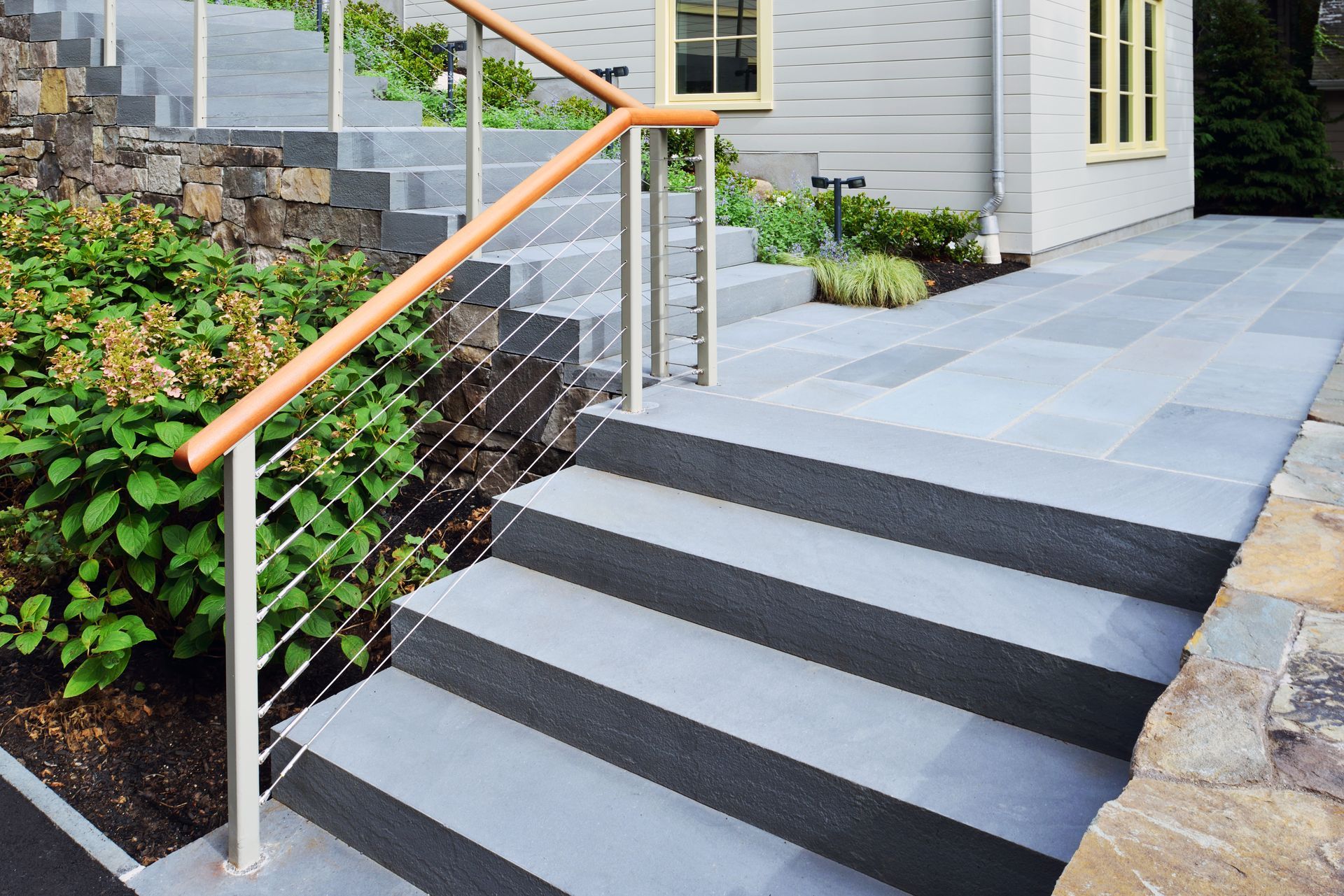 A set of stairs leading up to a house with a stainless steel railing