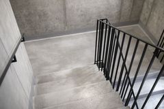 A staircase with a black railing and a concrete floor.