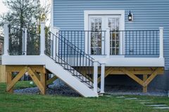 A blue house with a wooden deck railing and stairs leading up to it.